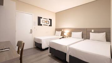 A hotel room with two single beds, a desk, and a chair.