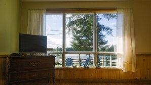 A room with a large window, wooden furniture, and a television on a dresser. - C1 Spacious Cottage - Nature Getaway in Peaceful Northern Ontario (Cobalt)