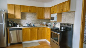 A kitchen with wooden cabinets, a stainless steel refrigerator, a dishwasher, a microwave, a stove, and a sink. - C1 Spacious Cottage - Nature Getaway in Peaceful Northern Ontario (Cobalt)