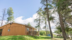 A wooden cabin with a balcony, surrounded by trees and a grassy area. - C1 Spacious Cottage - Nature Getaway in Peaceful Northern Ontario (Cobalt)