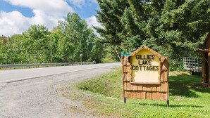 A wooden sign for 'Gillies Lake Cottages' by a road with a guardrail and trees in the background. - C1 Spacious Cottage - Nature Getaway in Peaceful Northern Ontario (Cobalt)