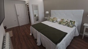 Ein Schlafzimmer mit Bett, Nachttisch, Spiegel und einer Tür.