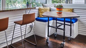 Habitación en esquina con asiento junto a la ventana, una mesa y sillas.