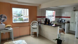 Cocina compacta con comedor, un ventilador y vistas de la ciudad a través del ventanal.