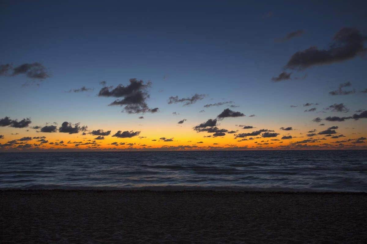 Una playa con un atardecer y nubes.