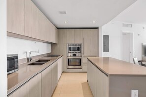 A modern kitchen with built-in appliances, a central island, and a minimalist design. - Luxurious Ocean View 2 Bedroom Escape (Hollywood)