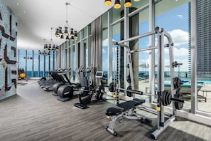 Academia com equipamentos de cardio, máquinas de musculação e um banco de supino.