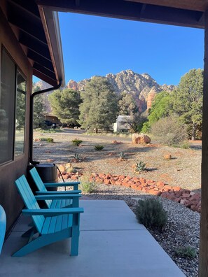 Eine Terrasse mit einem blauen Adirondack-Sessel, einem Betonweg und Blick auf rote Felsformationen und Bäume.