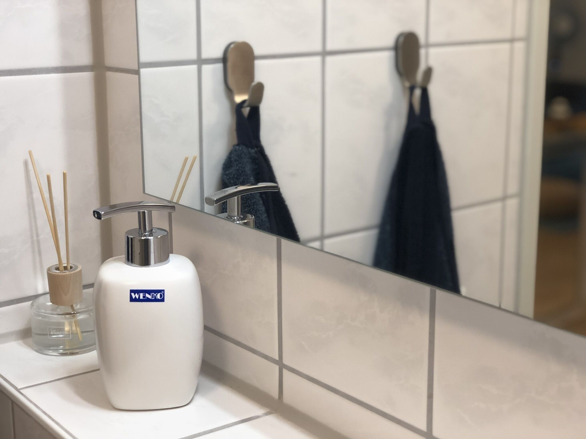 Ein Badezimmer mit einem weißen Waschbecken, einem Spiegel und einem Handtuchhalter.