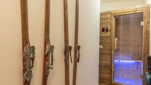 Un couloir avec des paires de skis en bois accrochées au mur et une porte en bois à l’arrière-plan.