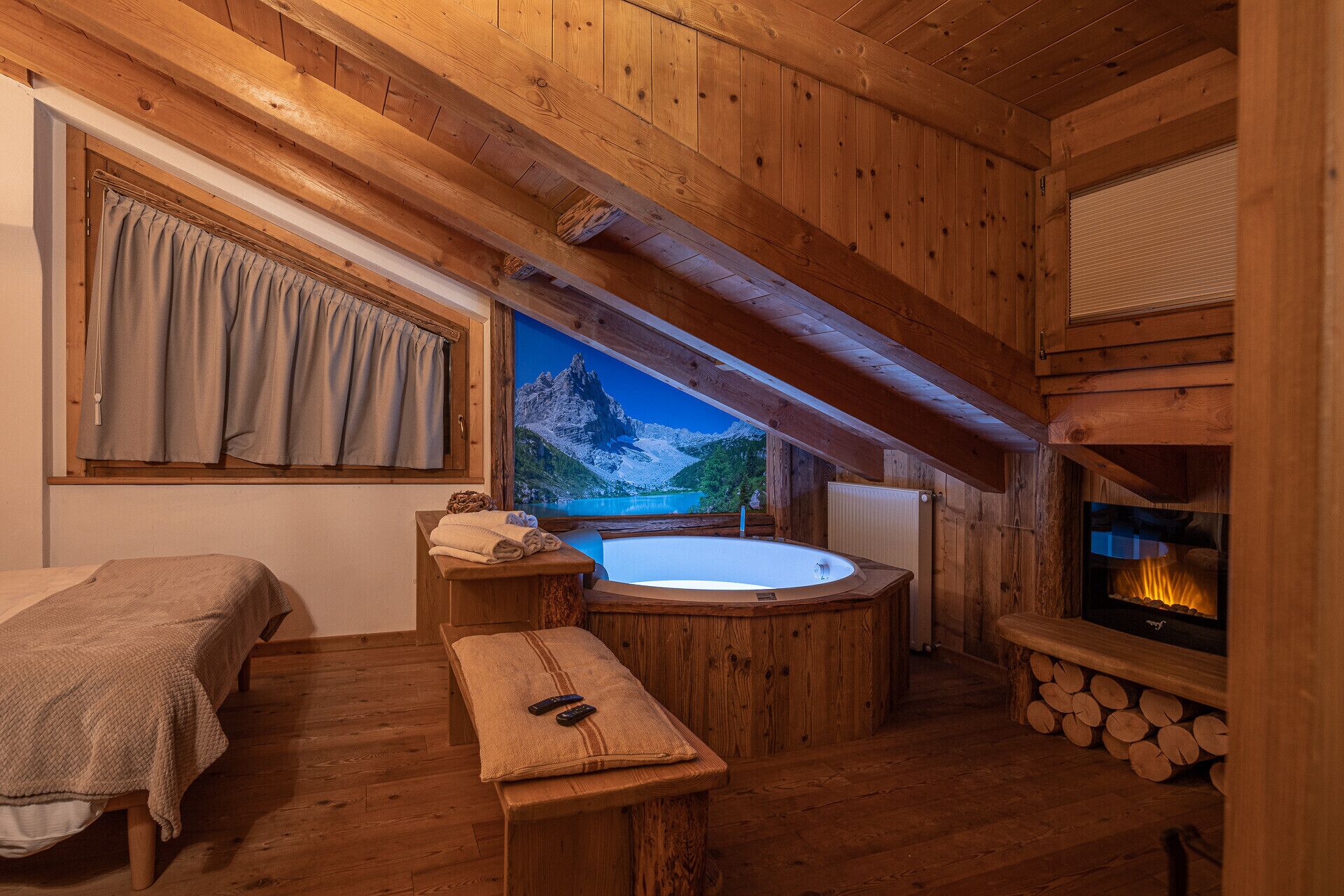 Una habitación de cabaña acogedora con interior de madera, un ventanal con vistas panorámicas a la montaña, chimenea y un jacuzzi.