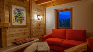 A cozy cabin interior with a wooden bench, a red sofa, and a framed painting on the wall. - Ciandolada 2 Wellness (Vodo Cadore)