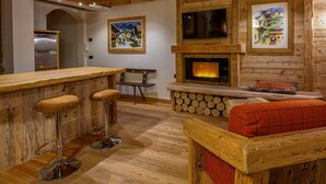 A wooden interior with a bar area, seating, a fireplace, and artwork on the walls. - Ciandolada 2 Wellness (Vodo Cadore)