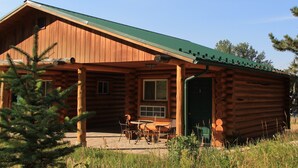 A log cabin with a green roof, a porch with chairs, and a door marked with the number 3. - Liberty Belle Lodge (Aladdin)