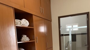 Un pasillo con un armario de madera, un vidrio que da a un baño y piso de baldosas.