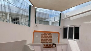 Una habitación con suelo de baldosas, un banco, una chimenea de ladrillo y una ventana.