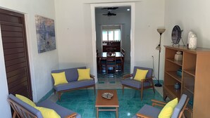 Una sala de estar con un sofá, sillones, una mesita de centro y una estantería.