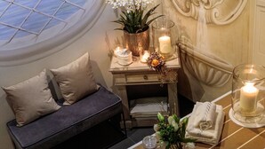 Quarto com janela arredondada, sofá, mesa com velas e decoração na parede.