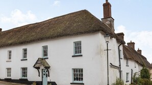 A traditional white building with a thatched roof, a small porch, and a street lamp. - Sheepwash Square House (Sheepwash, near Beaworthy)