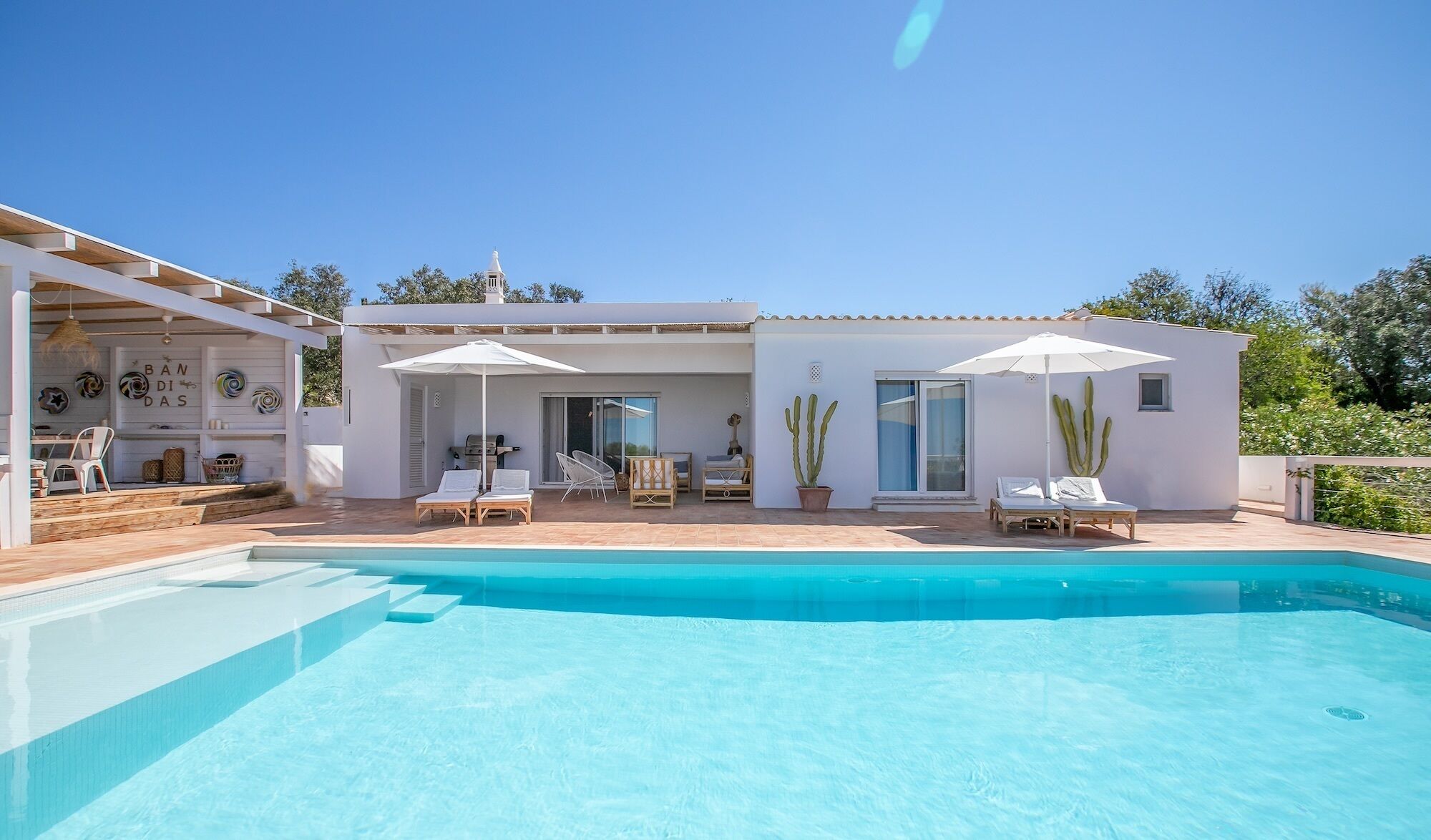 A modern house with a swimming pool, outdoor seating, and a garden.