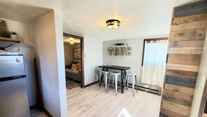 A compact living space with a kitchenette, a dining area, and a small seating area. - The Rustic Valley Cabin (Challis)
