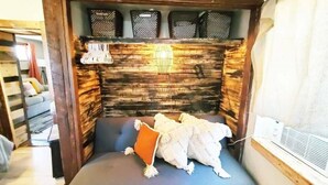 A cozy room with a built-in bench, a small table, and a window with blinds. - The Rustic Valley Cabin (Challis)