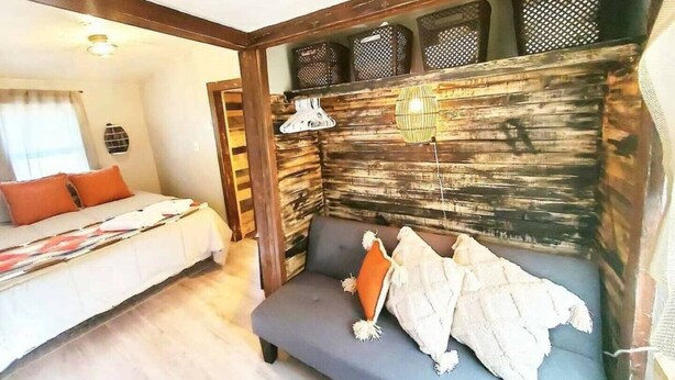 A room with a bed, a sofa, a lamp, and a wall with a textured pattern. - The Rustic Valley Cabin (Challis)