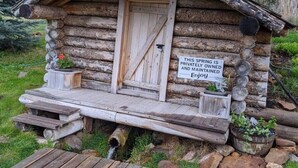 A rustic log cabin with a wooden door and a sign stating the spring is privately owned. - The Rustic Valley Cabin (Challis)