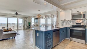 A spacious kitchen with a large island, stainless steel appliances, and a view to the outside.