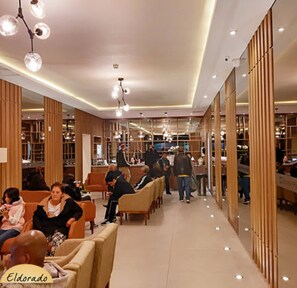 Un interior moderno con zonas de estar, paneles de madera e iluminación colgante.