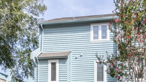 Ein zweistöckiges Wohnhaus mit Garage, einem kleinen Vorgarten und einem Baum mit rosafarbenen Blüten.