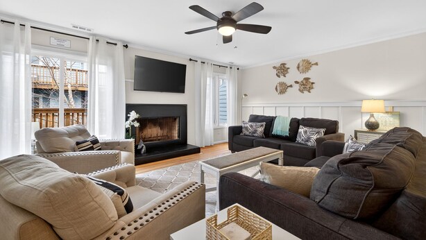 Ein Wohnzimmer mit Kamin, zwei Sofas, einem Couchtisch und einem Deckenventilator.