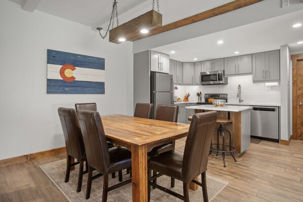 A modern kitchen with grey cabinets, a stainless steel refrigerator, and a microwave.