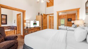 A hotel room with a large bed, a wooden desk, a chair, a television, and a bathroom visible through an open door. - Lovely Cabin in the Heart of Branson! Gas Fireplace & Jetted Tub, Ticket/Golf Discounts (Branson)