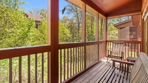 A wooden deck with a bench and table, surrounded by a wooden railing, overlooking a forested area. - Lovely Cabin in the Heart of Branson! Gas Fireplace & Jetted Tub, Ticket/Golf Discounts (Branson)