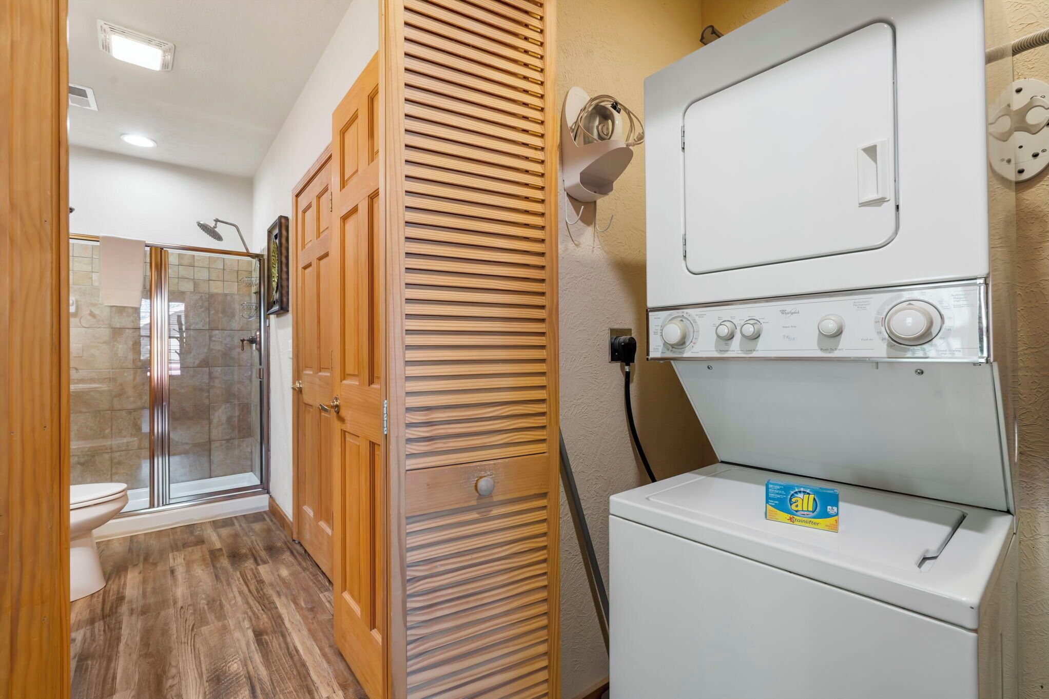 A compact bathroom with a shower, toilet, and a washing machine.