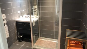 Une salle de bain moderne avec une douche à parois de verre, un lavabo blanc et un porte-serviettes.