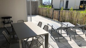 Une terrasse extérieure avec une table et des chaises, une petite table avec une chaise, et une clôture en bois.