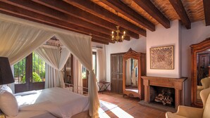 Un dormitorio con cama, chimenea y un espejo grande.