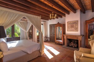 Un dormitorio con cama, chimenea y un espejo grande.
