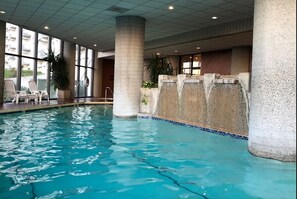 Relax by the rectangular pool surrounded by a tiled edge, with a soothing water feature nearby.