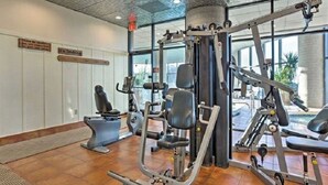 Ein Fitnessraum mit Trainingsgeräten, einem Rauchverbotsschild und großen Fenstern.