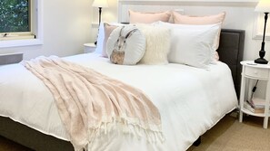 A neatly made bed with a fluffy blanket, white and peach pillows, and a decorative pillow with a rabbit design. - Autumn Beauty - Country Cottage 7 (Bright)
