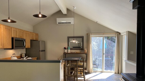 Una cocina con armarios de madera, microondas, refrigerador, estufa y comedor con mesa y sillas.