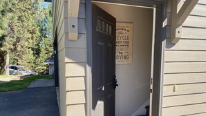 Una entrada de casa con una puerta abierta, un buzón y un cartel en la pared.