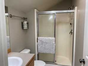 A modern bathroom with a glass-enclosed shower, a toilet, and a sink. - Hillside Loft- Spacious Studio, 100+mbps Wifi, Gas Fireplace, AC, Balcony (Bend)