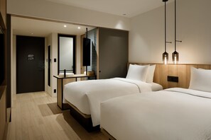 Ein modernes Hotelzimmer mit zwei Betten, einem hölzernen Kopfteil, einem Nachttisch und einem Spiegel.