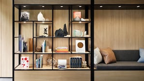 Un intérieur moderne avec une bibliothèque en bois, un canapé et une étagère murale sur laquelle sont disposés divers objets.
