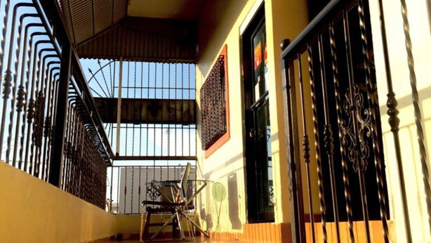 A staircase with a metal railing leading to a balcony with a view of the sky. - Hotel Verano Azul (Santo Domingo)