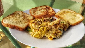 A plate with toast and scrambled eggs on a glass table. - Hotel Verano Azul (Santo Domingo)